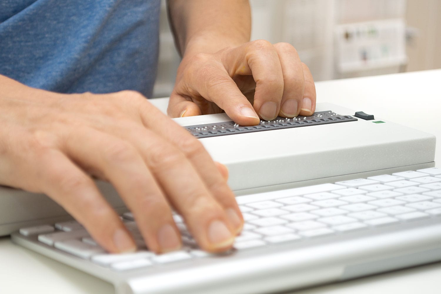 Blind person working on computer with braille keyboard